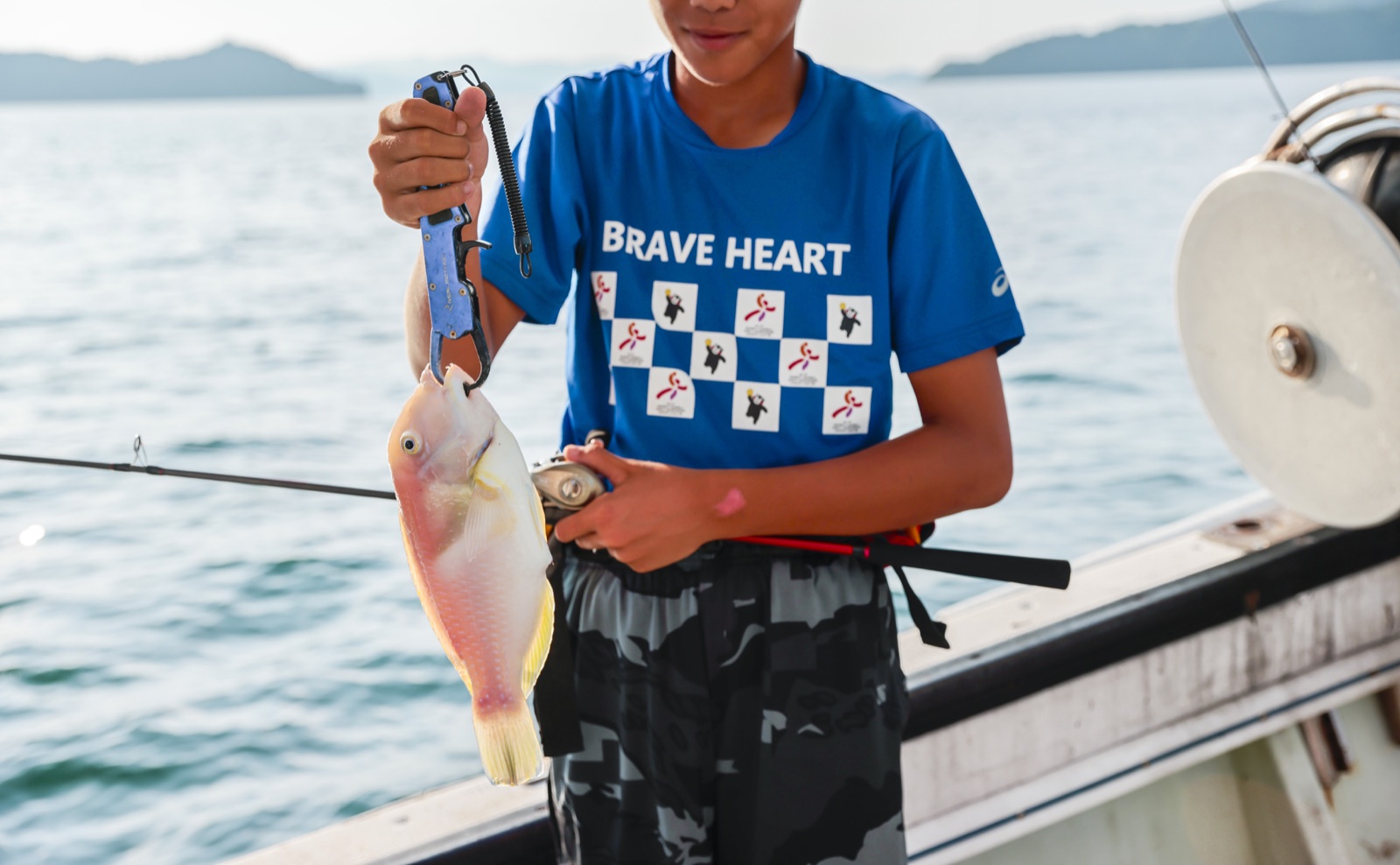 船釣りで釣った魚を手にする子ども