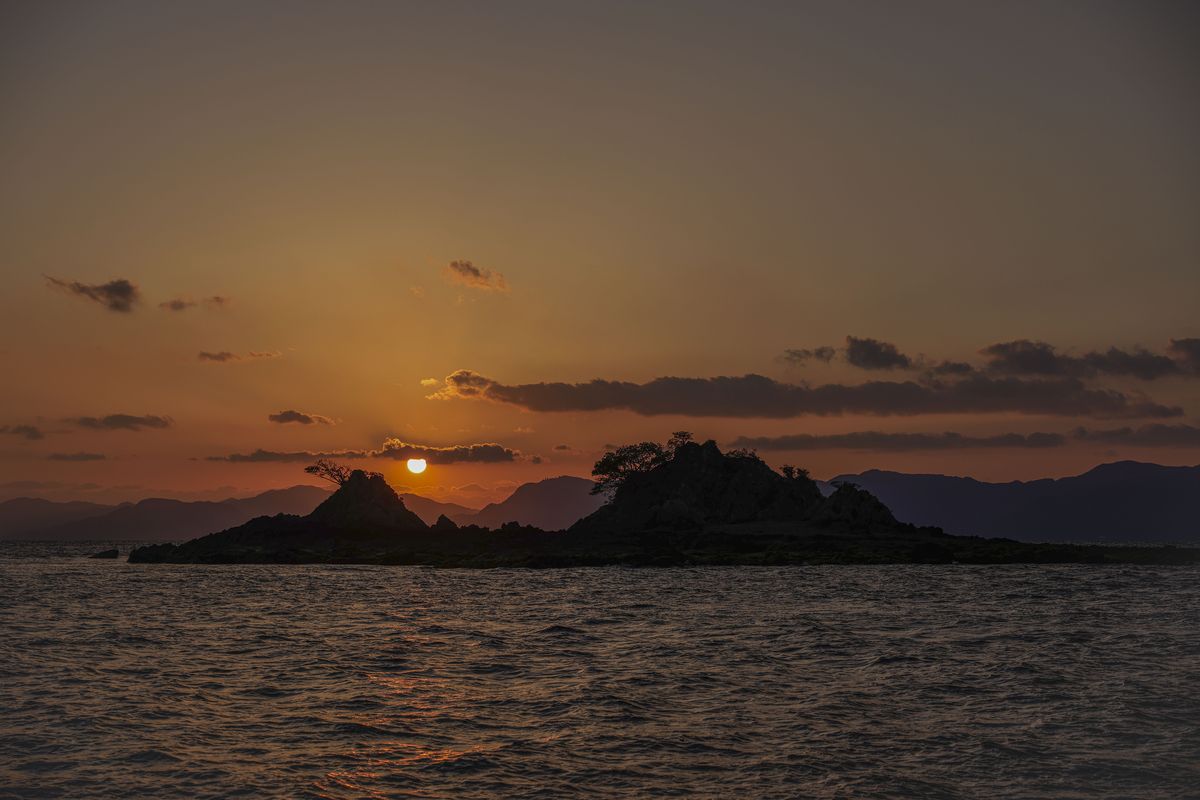 岩島の向こうに沈む夕日と、暮れていく海
